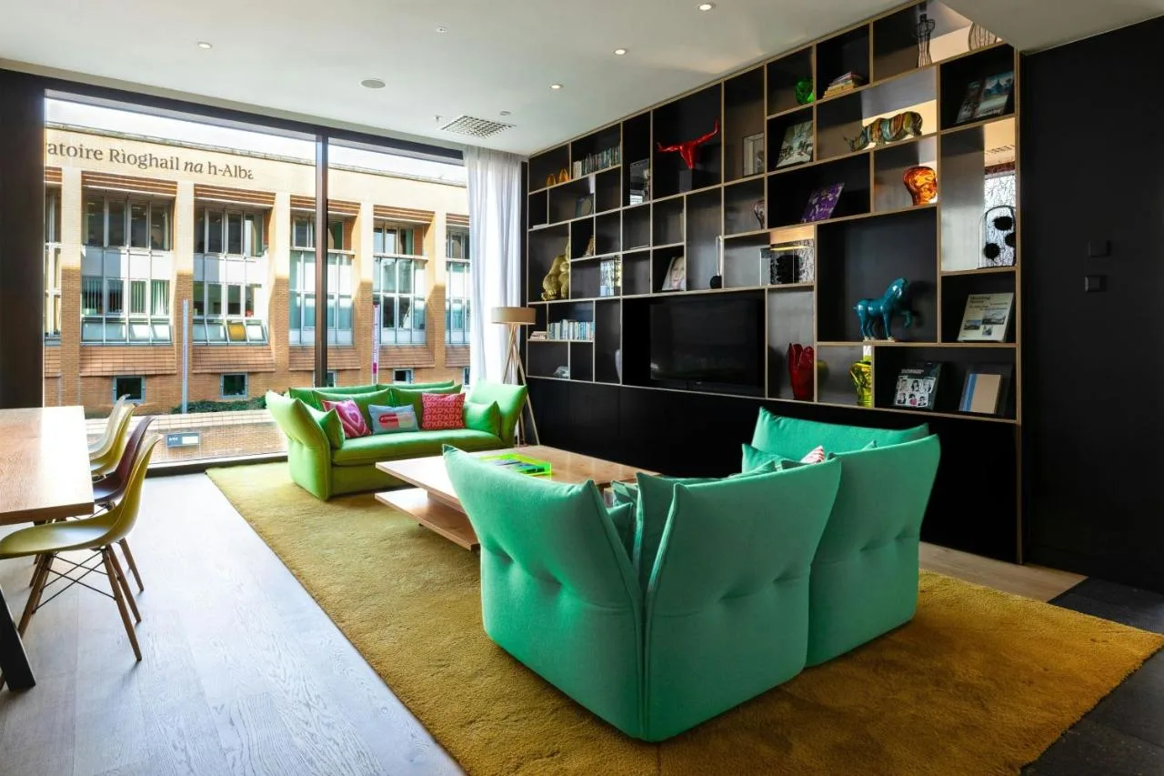a living room with green chairs and a table at citizenM Glasgow in Glasgow