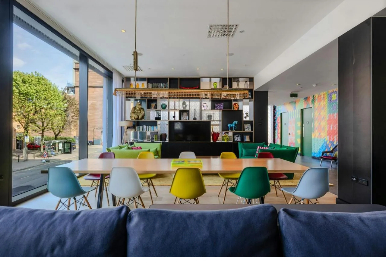 a living room with a couch and tables and chairs at citizenM Glasgow in Glasgow