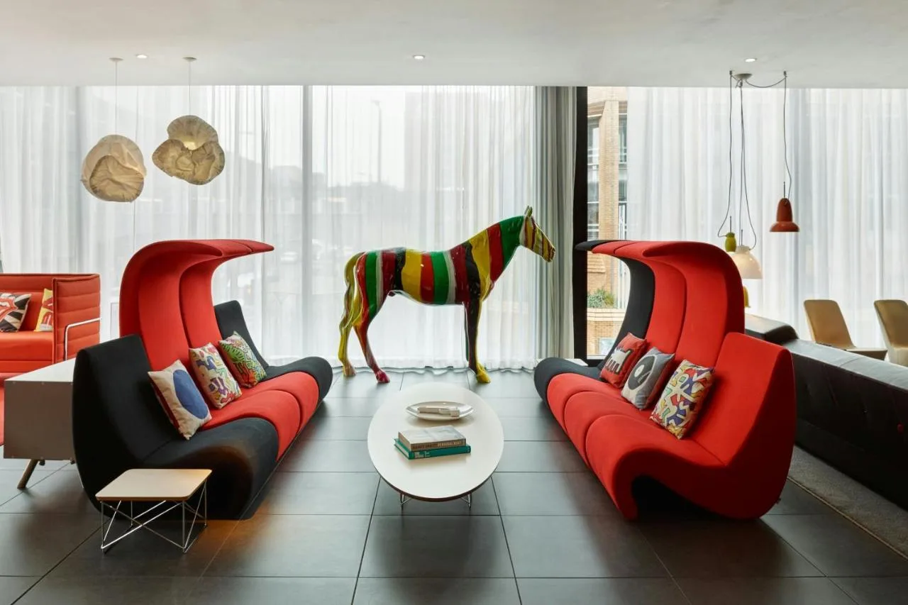 a living room with two red couches and a horse statue at citizenM Glasgow in Glasgow