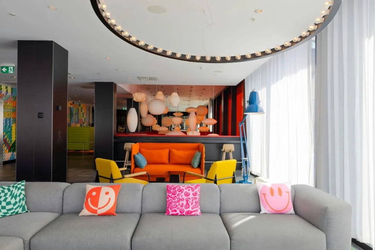 a living room with a gray couch with colorful pillows at citizenM Glasgow in Glasgow