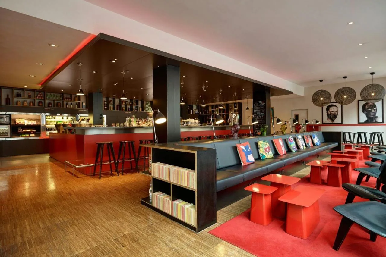 a bar with red tables and red stools at citizenM Glasgow in Glasgow